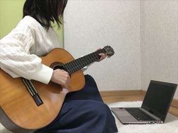 ギターで作曲する女性